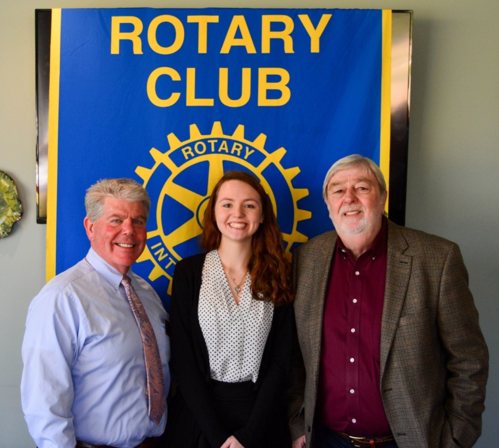 female STAR student posed with two men in front of Rotary Club banner